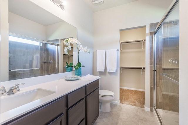 bathroom featuring toilet, a shower stall, tile patterned flooring, a spacious closet, and vanity