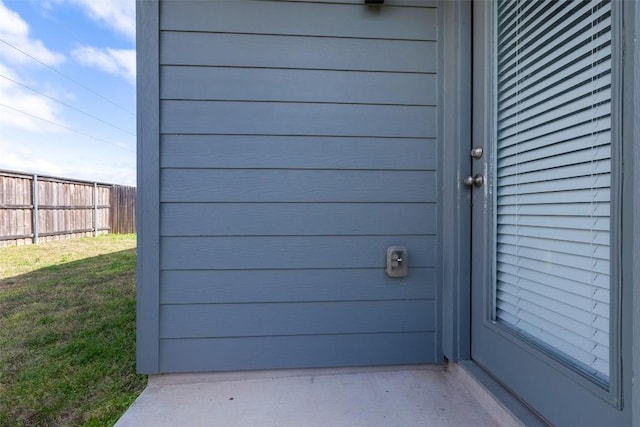 doorway to property featuring a lawn and fence