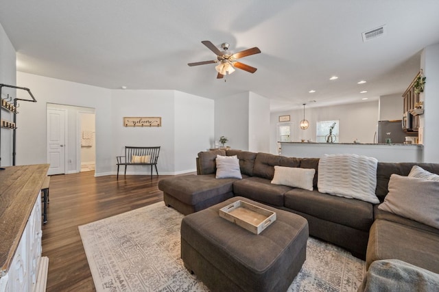 living room featuring a ceiling fan, visible vents, baseboards, recessed lighting, and dark wood-style flooring