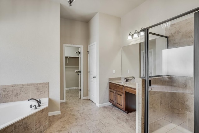 bathroom featuring vanity, a walk in closet, a bath, and a stall shower