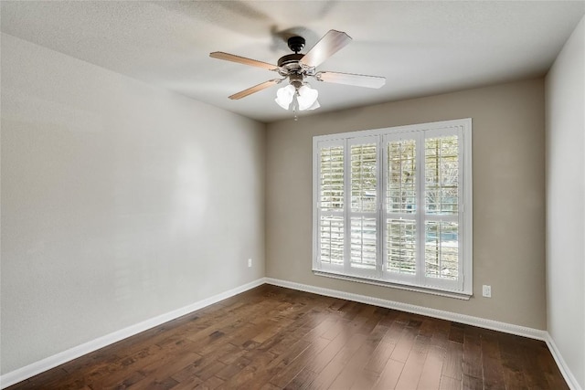 empty room featuring dark wood-type flooring, baseboards, and ceiling fan