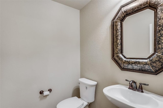 half bathroom featuring toilet and a sink