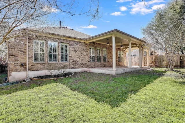 rear view of house featuring a patio, fence, a yard, brick siding, and ceiling fan