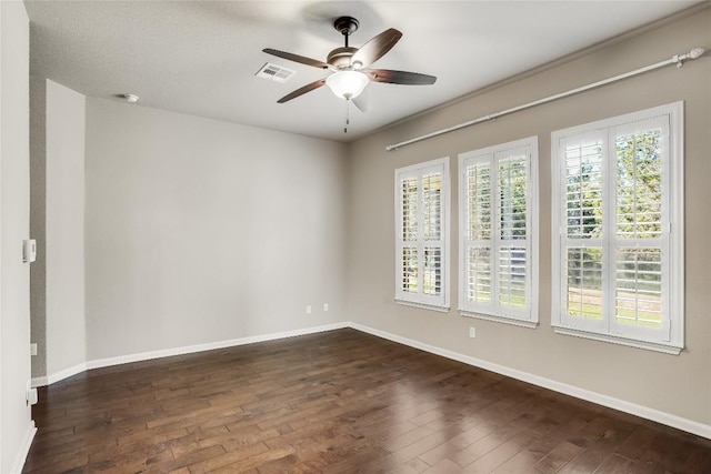 empty room featuring visible vents, a ceiling fan, dark wood-type flooring, and baseboards