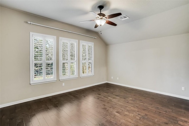 spare room with a wealth of natural light, visible vents, lofted ceiling, and dark wood-style flooring