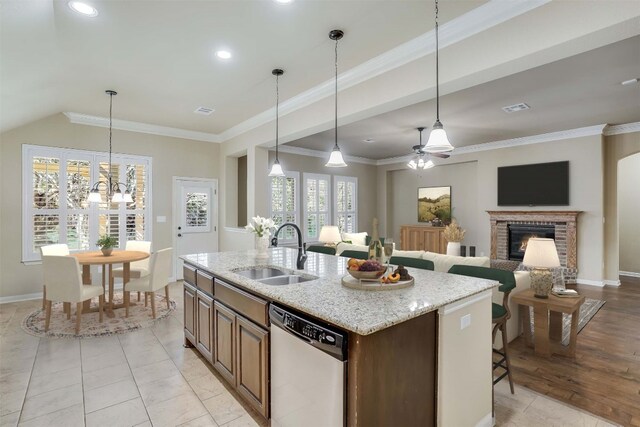 kitchen featuring a kitchen island with sink, ornamental molding, a sink, a fireplace, and dishwasher