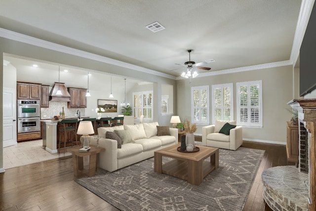 living room with hardwood / wood-style floors, visible vents, and ornamental molding