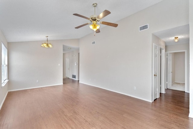 unfurnished room featuring visible vents, lofted ceiling, wood finished floors, and ceiling fan with notable chandelier