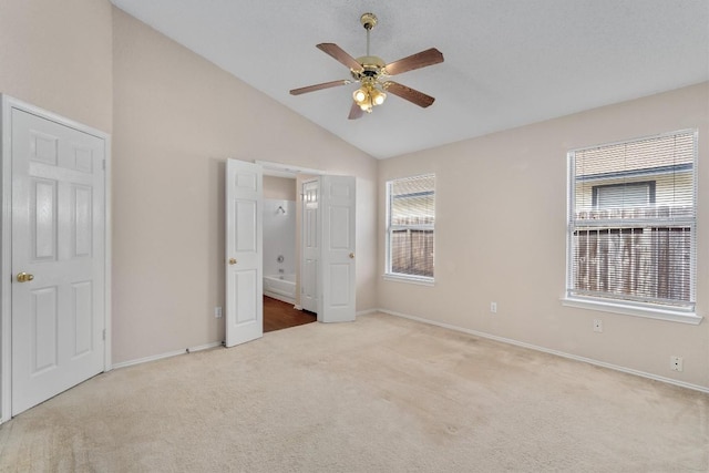 unfurnished bedroom featuring connected bathroom, lofted ceiling, baseboards, and carpet flooring