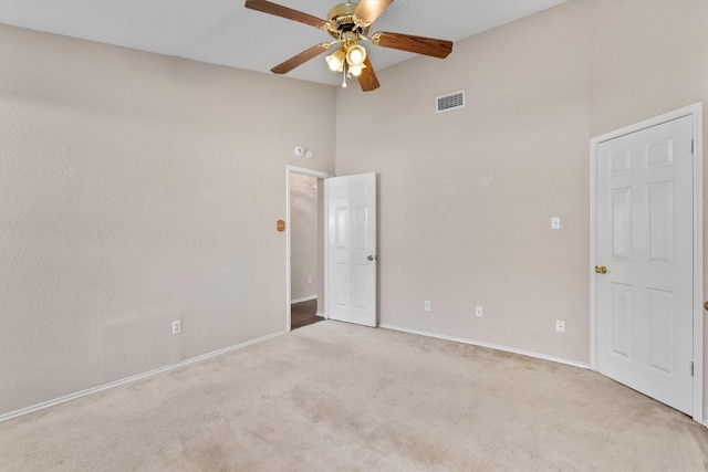 spare room featuring baseboards, visible vents, high vaulted ceiling, carpet floors, and ceiling fan