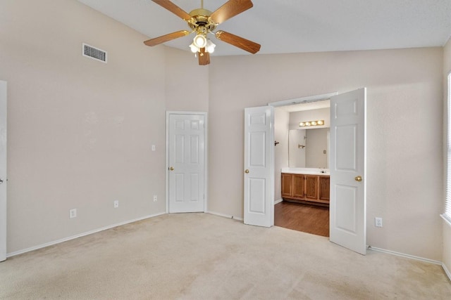 unfurnished bedroom with visible vents, ensuite bathroom, baseboards, light colored carpet, and vaulted ceiling