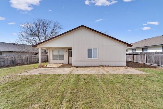 rear view of house with a fenced backyard, a lawn, and a patio