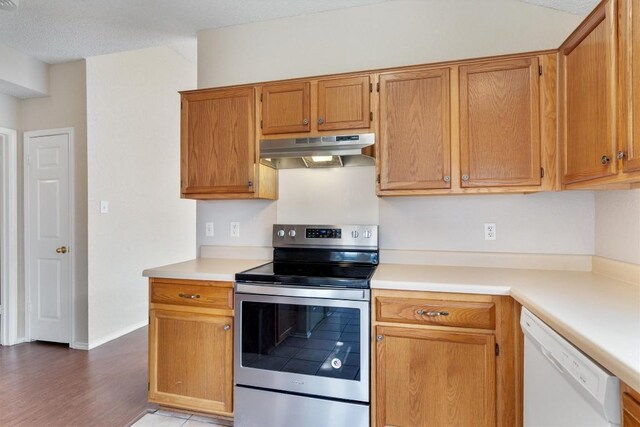 kitchen featuring brown cabinetry, stainless steel electric stove, light countertops, under cabinet range hood, and dishwasher