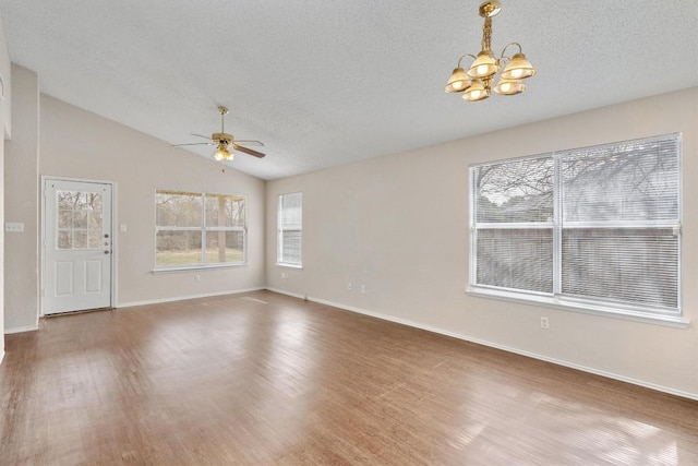 empty room featuring baseboards, vaulted ceiling, ceiling fan with notable chandelier, wood finished floors, and a textured ceiling