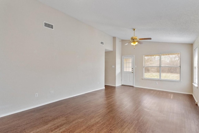 unfurnished room with visible vents, a textured ceiling, wood finished floors, and vaulted ceiling