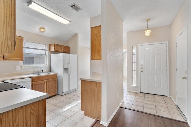 kitchen with visible vents, light countertops, light tile patterned floors, white fridge with ice dispenser, and a textured ceiling