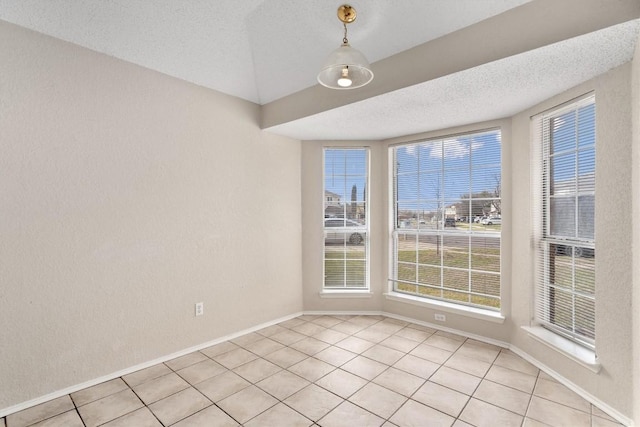 unfurnished room with light tile patterned floors, baseboards, and a textured ceiling