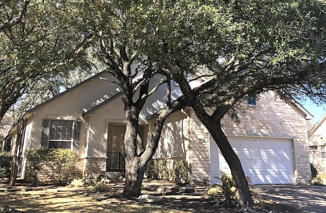 view of front of house with concrete driveway, an attached garage, stone siding, and stucco siding