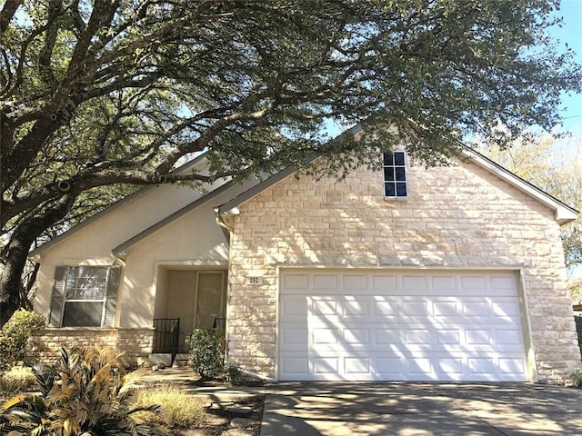 view of front of home featuring stone siding, stucco siding, driveway, and an attached garage