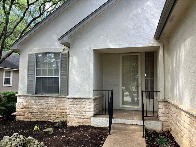 property entrance with stone siding and stucco siding