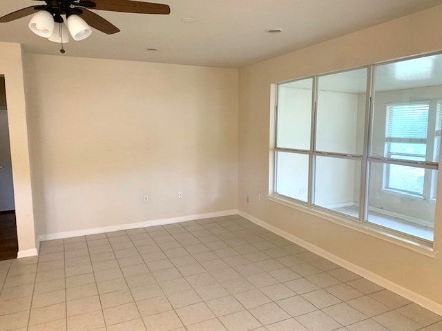 unfurnished room featuring plenty of natural light, a ceiling fan, baseboards, and light tile patterned flooring