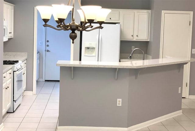 292 Whispering Wind Dr, Georgetown, TX 78633 - kitchen with white appliances, light tile patterned floors, a chandelier, white cabinets, and a breakfast bar area