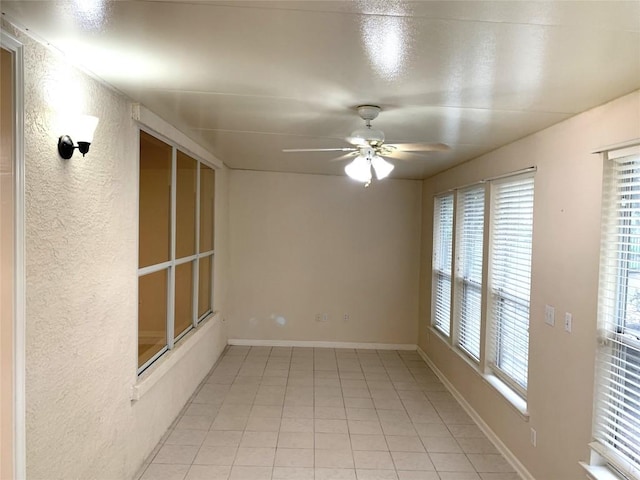 spare room with light tile patterned floors, baseboards, and ceiling fan