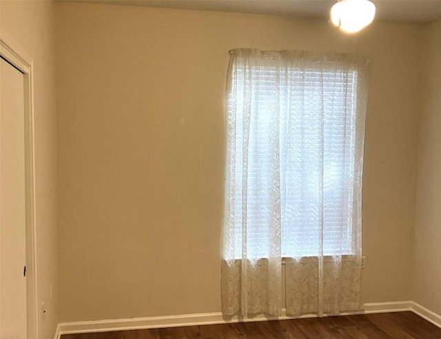 unfurnished room with dark wood-style floors and baseboards