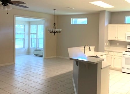 kitchen with light countertops, light tile patterned floors, white cabinets, white appliances, and a sink