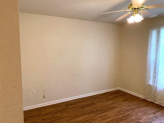 spare room featuring ceiling fan, dark wood-type flooring, and baseboards