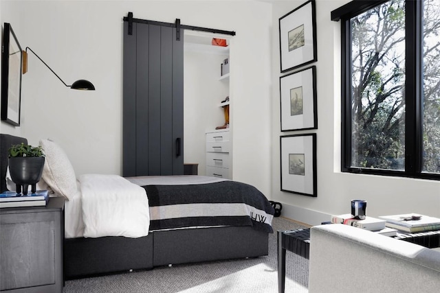 bedroom with a barn door, carpet flooring, and baseboards