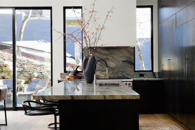 bar featuring tasteful backsplash, light wood-type flooring, and a sink