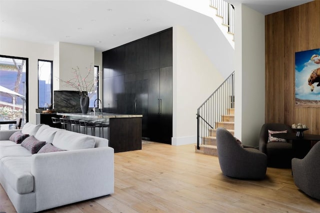 living room featuring stairway, light wood-type flooring, and wood walls