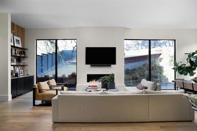 living room with light wood-style flooring, bar area, and a lit fireplace