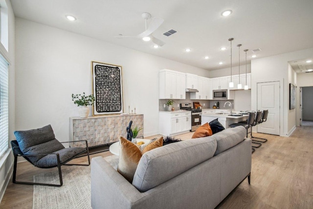 living room featuring recessed lighting, visible vents, and light wood-type flooring