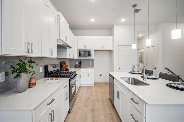 kitchen featuring visible vents, under cabinet range hood, appliances with stainless steel finishes, white cabinetry, and a sink