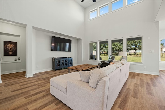 living area featuring a ceiling fan, baseboards, and wood finished floors