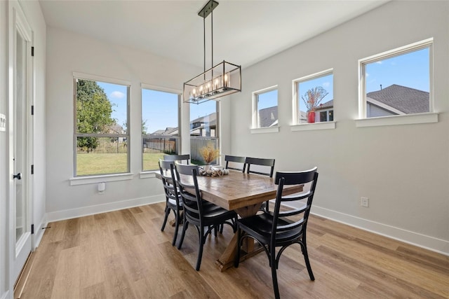 dining space with light wood-style flooring, an inviting chandelier, and baseboards