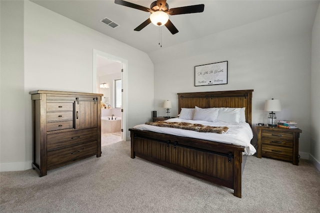 bedroom with visible vents, light colored carpet, ensuite bath, and lofted ceiling