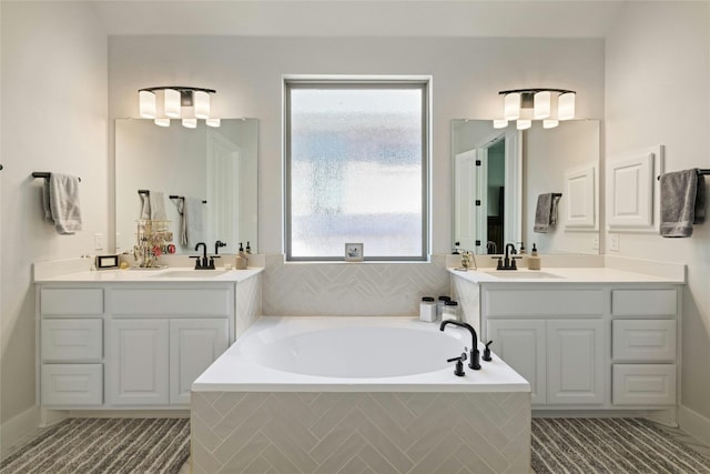 full bathroom with a garden tub, two vanities, and a sink