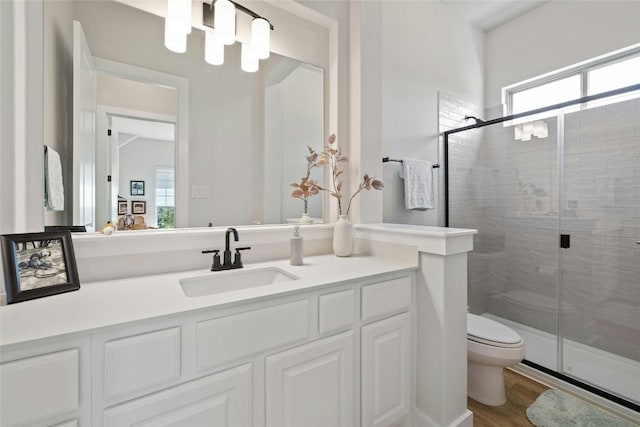 full bathroom featuring vanity, toilet, wood finished floors, and a stall shower