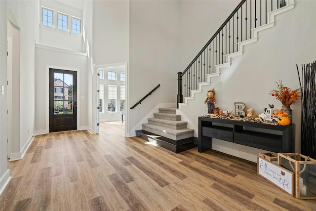 entryway featuring baseboards, a high ceiling, wood finished floors, and stairs