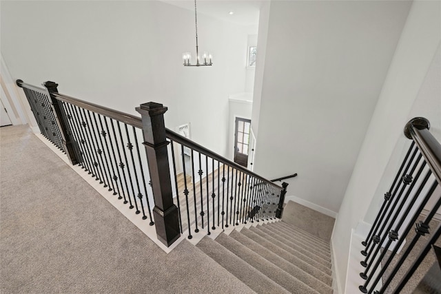 stairs with baseboards, a notable chandelier, a towering ceiling, and carpet flooring