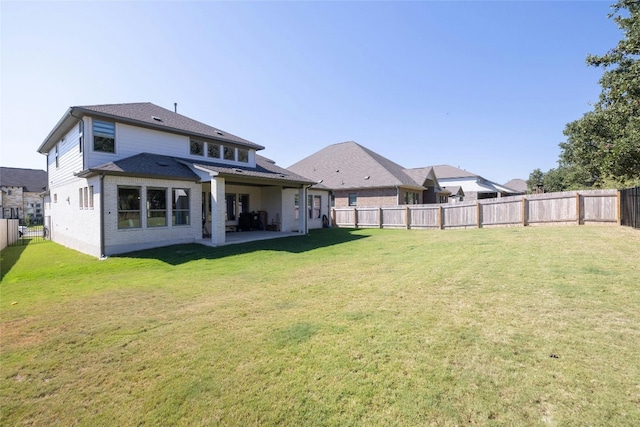 rear view of property featuring brick siding, a fenced backyard, and a yard