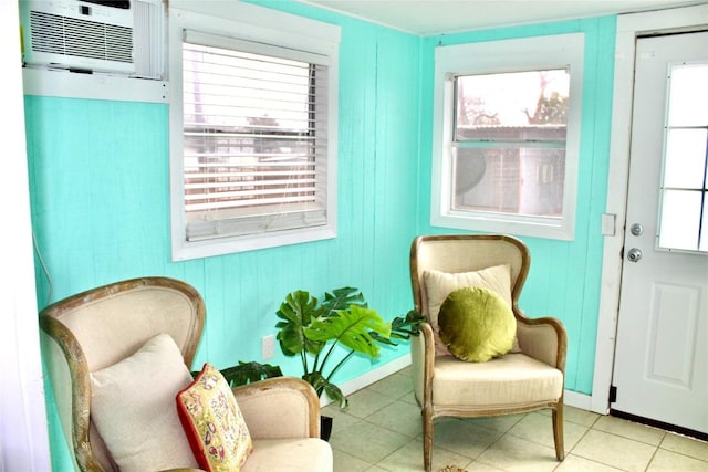 living area featuring baseboards, an AC wall unit, and tile patterned flooring