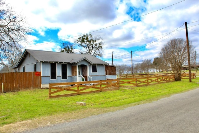 view of front of home with metal roof, a front yard, and fence