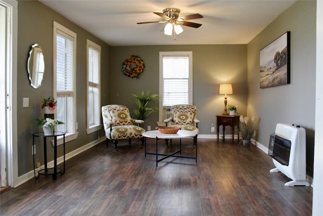 sitting room with heating unit, dark wood finished floors, a ceiling fan, and baseboards