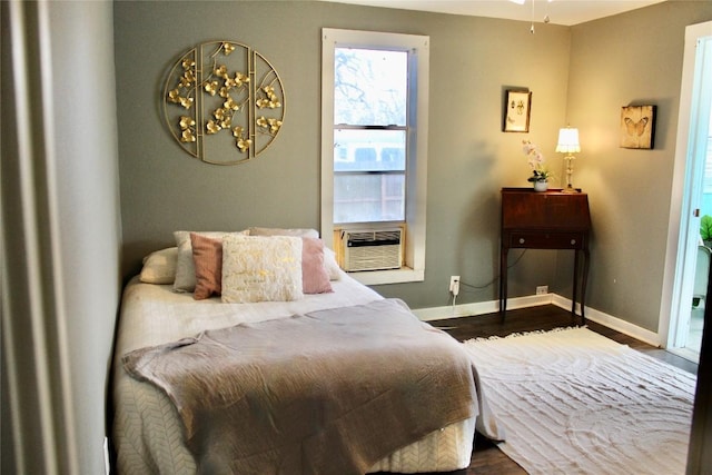 bedroom with cooling unit, baseboards, and dark wood-style flooring