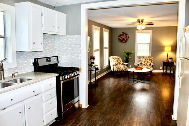 kitchen with stainless steel gas stove, a sink, dark wood-style floors, freestanding refrigerator, and light countertops