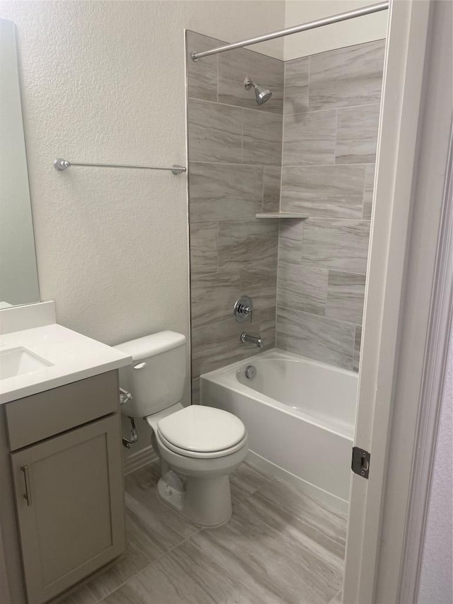 bathroom with vanity, toilet, a textured wall, and shower / bathtub combination